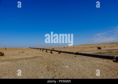 Remote deserto del Namib con sopra la terra tubo di ferro che si estende su per trasportare acqua da impianto di desalinizzazione di Swakopmund alla miniera di uranio. Costruito con chi Foto Stock