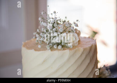Tre livelli di torta nuziale coperta in glassa di crema di burro e fiori reale Foto Stock