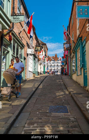 Coppia con passeggino rendendo la loro strada ripida collina Lincoln UK Maggio 2018 Foto Stock