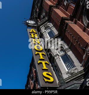 Shopping, cartello del grande magazzino Arnotts, facciata in pietra arenaria, Henry Street, Dublino, Irlanda, Europa. Cielo blu chiaro, spazio di copia, vista ad angolo basso. Foto Stock