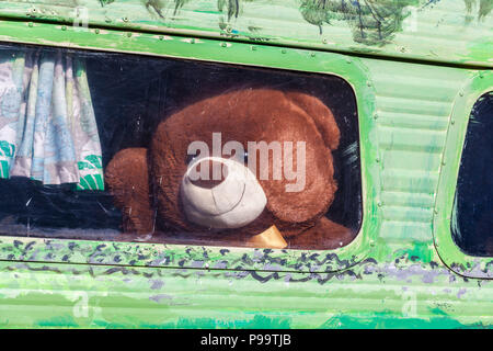 Big brown orsacchiotto sventolare dal vintage finestra caravan Foto Stock