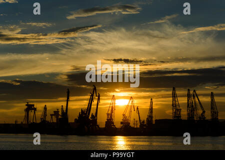 Silhouette di Gru nel porto di Varna al tramonto Foto Stock