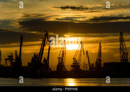 Silhouette di Gru nel porto di Varna al tramonto Foto Stock