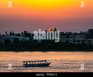 Colorato tramonto sul fiume Nilo, con battello fluviale silhouette, Luxor, Egitto, Africa Foto Stock