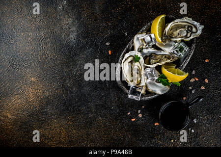 Freschi piatti di pesce crudo, ostriche con limone e ghiaccio su sfondo azzurro. Foto Stock