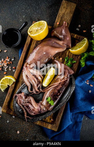 Freschi piatti di pesce crudo, calamari con limone e la luce per la preparazione su sfondo azzurro.