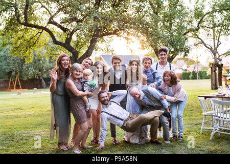 Sposa e lo sposo e gli ospiti che posano per una foto al ricevimento di nozze al di fuori nel cortile. Foto Stock