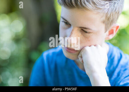 Close up infelice ragazzo adolescente seduti all'aperto Foto Stock