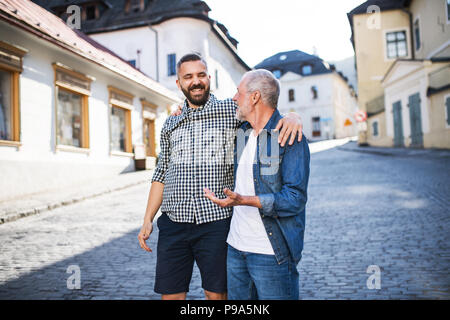 Un adulto hipster figlio col padre senior in una passeggiata nella città. Foto Stock