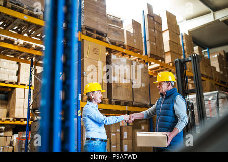 Donna senior manager o dei lavoratori che lavorano in un magazzino, stringono le mani. Foto Stock