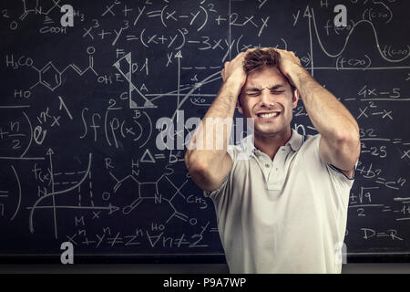 Hanno sottolineato i giovani studenti caucasici e sfondo della lavagna Foto Stock
