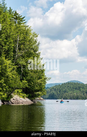 Kayaker femmina su un laghetto remoto nel deserto Adirondack Foto Stock