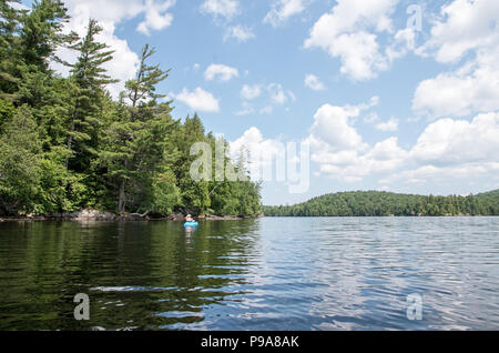 Kayaker femmina su un laghetto remoto nel deserto Adirondack Foto Stock