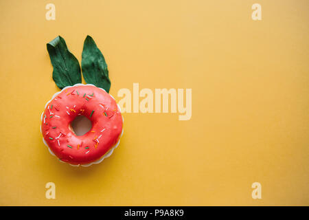 Una ciambella di creativi con le orecchie di foglie che assomigliano a un coniglio su uno sfondo giallo in stile minimale. Foto Stock