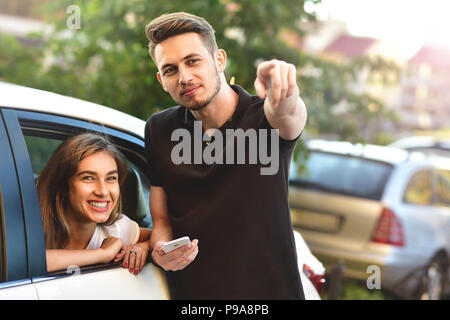 Bella ragazza seduta in auto e flirtare con il ragazzo che permanente all'aperto Foto Stock