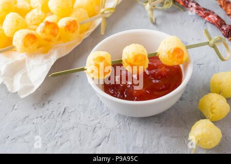 Formaggio palline di mais con il piccante salsa di pomodoro. Foto Stock