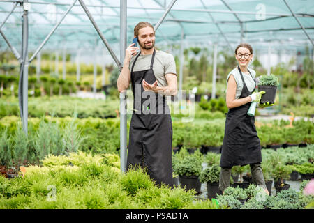 Giardiniere parlando telefono in serra Foto Stock