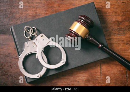 La legge e l'ordine del concetto. Manette, martello sul libro su un sfondo di legno, vista dall'alto Foto Stock