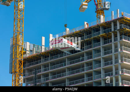 Il caricamento con gru piattaforma essendo sollevato in posizione in corrispondenza del duetto di blocchi di appartamenti di sviluppo, Bacino di Erie, Salford Quays, Manchester, Regno Unito Foto Stock