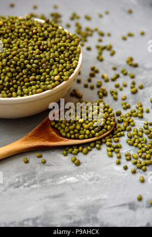 Vaso in ceramica di fagioli mung con il cucchiaio di legno sul cemento grigio sfondo Foto Stock