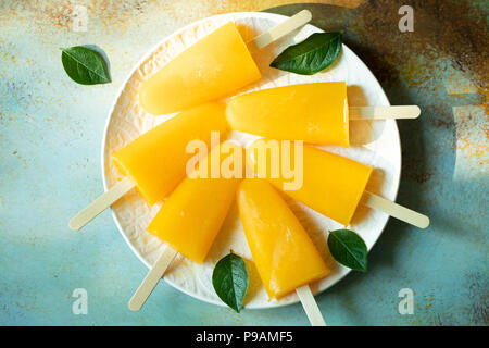 Popsicles arancione con il succo su un bacground blu. Ice pops, piatto di laici che, vista dall'alto. Foto Stock