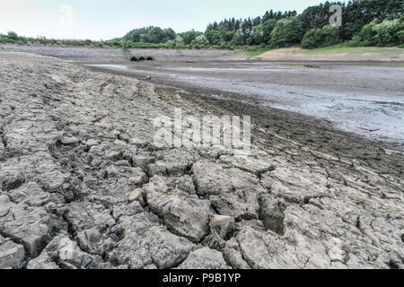 Serbatoio Wayoh, Entewistle, Nr Edgworth, Bolton, Lancashire, Regno Unito. Il 15 luglio 2018. Di proprietà di United Utilities. A causa di quasi un mese con un minimo di parti di pioggia del serbatoio hanno prosciugato completamente lasciando un letto di fango incrinato. Nonostante due giorni reecent dove il nord-ovest dell'Inghilterra ha visto una leggera pioggia, i livelli sono diminuiti drasticamente negli ultimi giorni con altre parti del serbatoio a rischio di diventare secca. Spaccature profonde sono apparsi. Credito: Phil Taylor/Alamy Live News Foto Stock