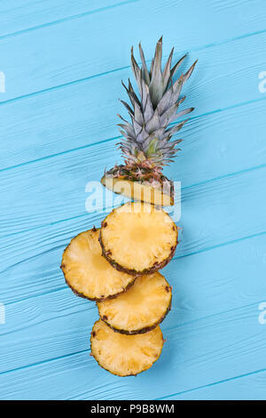 Mature a fette di ananas in pezzi, vista dall'alto. Piano di composizione dei laici con fresco di ananas a fette in blu sullo sfondo di legno. Foto Stock