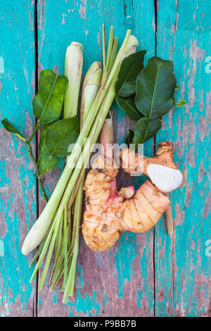 Galangal fresco con la citronella e foglie di combava dal di sopra su un tavolo di legno. Foto Stock