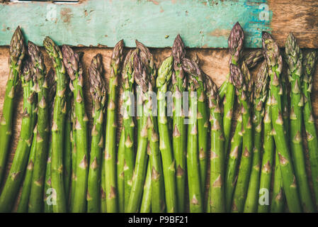 Materie non cotti asparagi verdi su in legno rustico sfondo vassoio, close-up Foto Stock