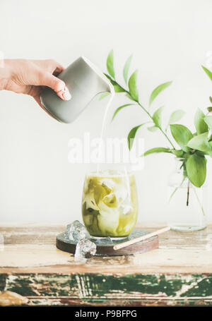 Iced matcha latte da bere con latte di cocco versare dal lanciatore Foto Stock