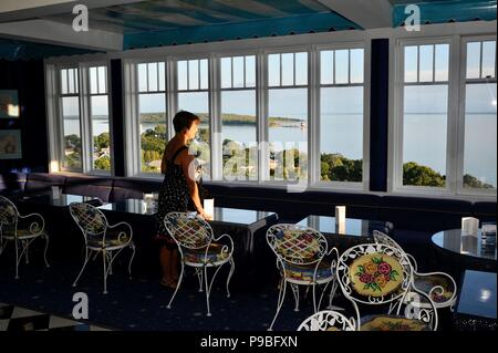 Donna che guarda fuori attraverso windows oltre il lago dalla cupola bar nello storico Grand Hotel il resort isola di Mackinac Island, Michigan, Stati Uniti d'America. Foto Stock