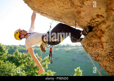 Immagine del rocciatore nel casco salire sulla montagna sullo sfondo di un paesaggio pittoresco Foto Stock