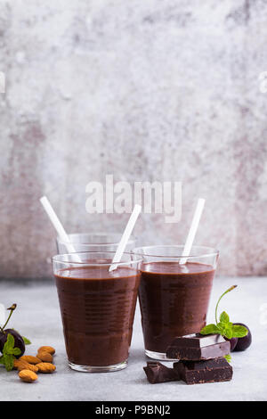 Frullati di cioccolato con ciliegie e mandorle. su un tavolo di pietra grigia. Vegano drink di proteine per gli atleti e i buongustai Foto Stock