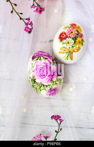 Decorate le uova di pasqua e fiori su tulle bianco sullo sfondo; tecnica decoupage Foto Stock