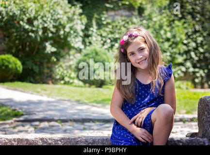 Ritratto di una bella sorridente bambina vestito blu, nel parco Foto Stock