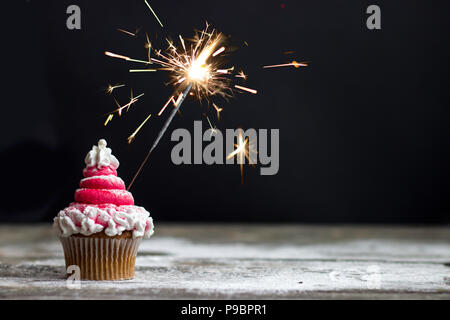 Tortina con rosso di glassa di turbolenza e sparkler, natale decorazione cupcake Foto Stock