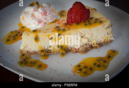 Fetta di frutto della passione torta di formaggio e rabboccato con una fragola Foto Stock