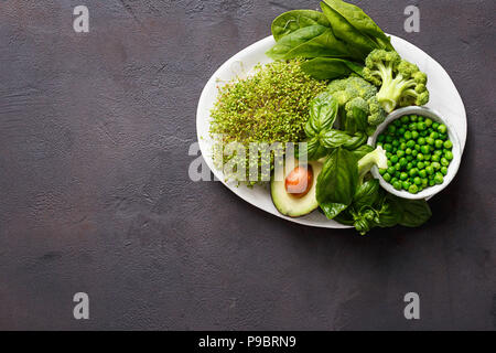 Cibo sano e pulito di mangiare la selezione fonte di proteine per i vegetariani: Lucerna, spinaci, basilico, piselli verdi, avocado e broccoli su sfondo scuro wi Foto Stock