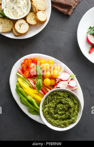 Spuntini salutari. Verdure crude, crostini di pane con il pesto e salsa di aglio in pietra nera di sfondo vista superiore Foto Stock