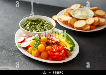 Snack sani per i vini. Verdure crude, crostini di pane con il pesto e salsa di aglio nero su sfondo di pietra Foto Stock