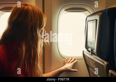 La donna in sedia a bordo di un aereo guardando fuori dalla finestra Foto Stock