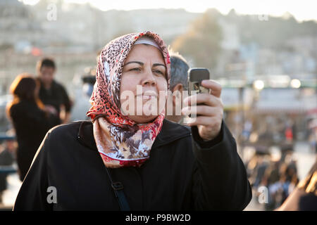 Istanbul, Turchia - 6 Novembre 2009: donna che indossa velo utilizza il suo cellulare per scattare una fotografia mentre sul Ponte di Galata a Istanbul Foto Stock