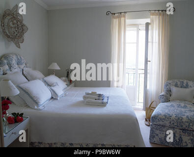 Blue rifilato cuscini bianchi e un letto bianco coperchio sul letto in camera da letto Toscana con un blu toile de Jouy chaise longue Foto Stock