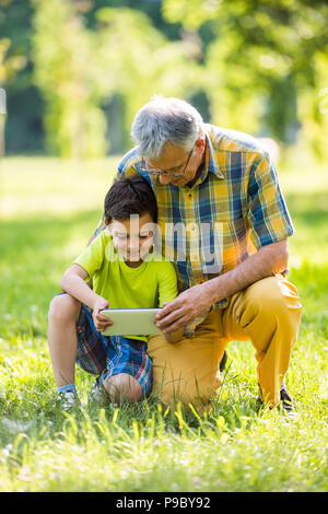 Nonno e nipote utilizzando digitale compressa in posizione di parcheggio Foto Stock