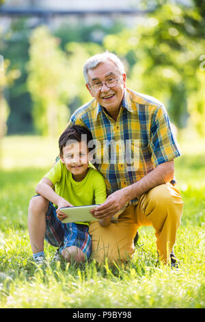 Nonno e nipote utilizzando digitale compressa in posizione di parcheggio Foto Stock