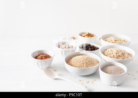 Varieta' di cereali grezzi e i dadi per la prima colazione. Fiocchi di avena e di acciaio tagliati, orzo, noce, chia, uvetta. Ingredienti sani Foto Stock