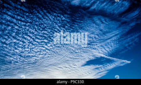 Una spettacolare inspirational vivacemente colorato atmosferica cielo nuvoloso cloudscape dotato di un cloud Cirrocumulus formazione in una metà del cielo blu. Australia. Foto Stock