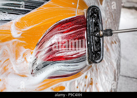 Pennello lasciando tratti nel sapone e schiuma di giallo auto lavata in autolavaggi. Foto Stock