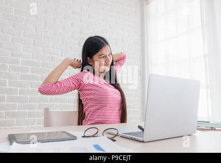 Donna asiatica freelancer braccio di estensione sul retro nella parte anteriore del computer portatile sulla scrivania da lavoro in ufficio a casa,lavoro a casa Foto Stock