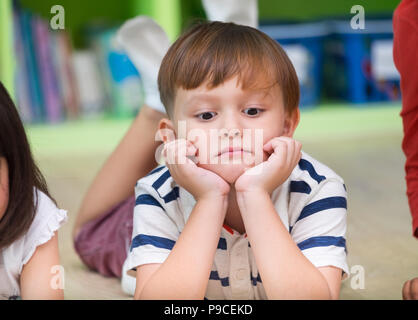 Boy kid stendo sul pavimento della libreria con sensazione di noia nella libreria di età prescolare,Kindergarten scuola educazione Nozione Foto Stock